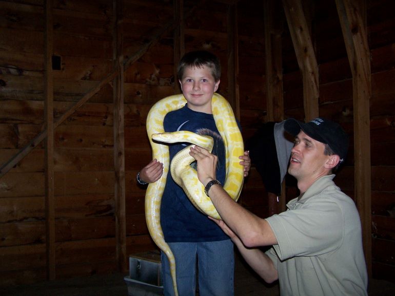 Boy holding giant snake around his neck