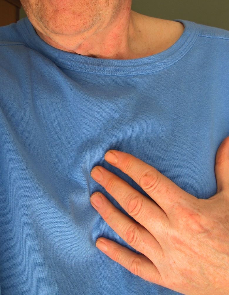 Man wearing blue shirt holding his heart