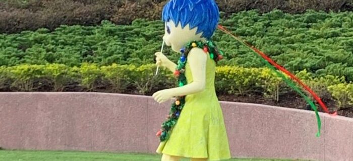 Disney character, Joy, from Inside Out walking through Disney World park.