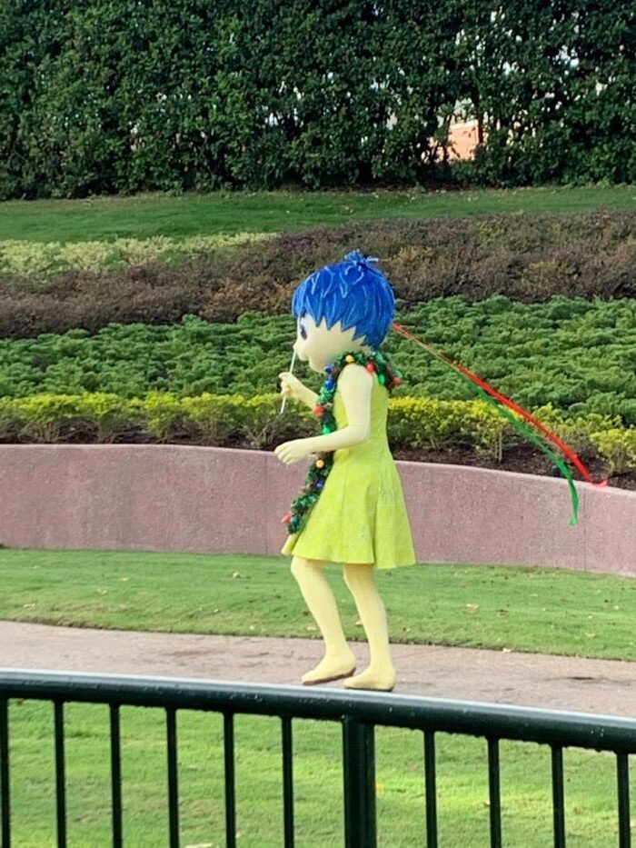 Disney character, Joy, from Inside Out walking through Disney World park.