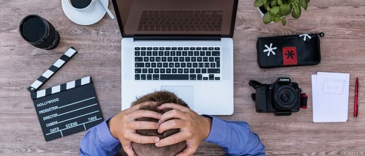 Frustrated man at his computer, hands on head