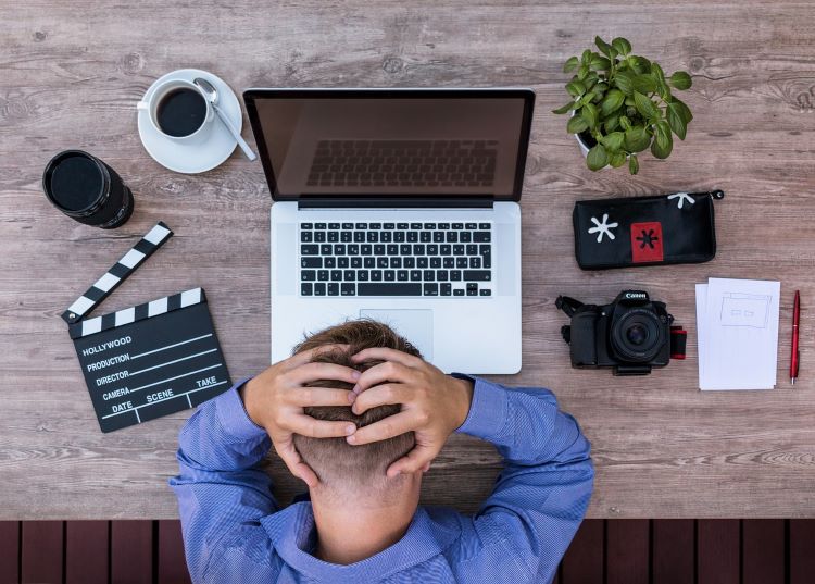 Frustrated man at his computer, hands on head